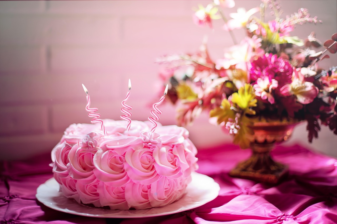 A decorated first birthday cake table with balloons and a banner